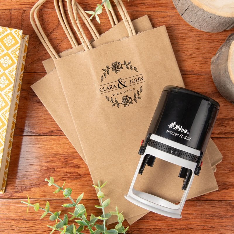 Shiny R-552 self-inking stamp displayed beside kraft gift bags stamped with a floral design