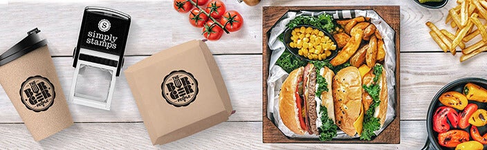 stamp body laying on table with food items that look to have been stamped by the business highlighting their branding on their food packaging. 