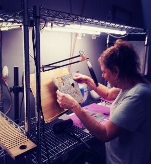Dottie leaning over a work bench looking at the rubber impressions that are ready to be separated